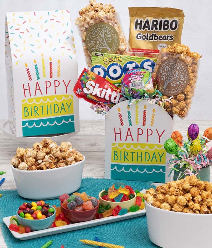 A gift box with a bag of skittles, kettlecorn, a box of DOTS, a bunch of Tootsie Pops, and a bag of haribo gummy bears