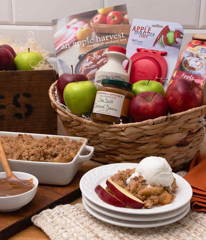 Gift basket with red and green apples, apple spiralizer & corer, An Apple Harvest: Recipes & Orchard Lore, apple crisp mix, a jug of apple cider concentrate, and a jar of sea salt caramel sauce