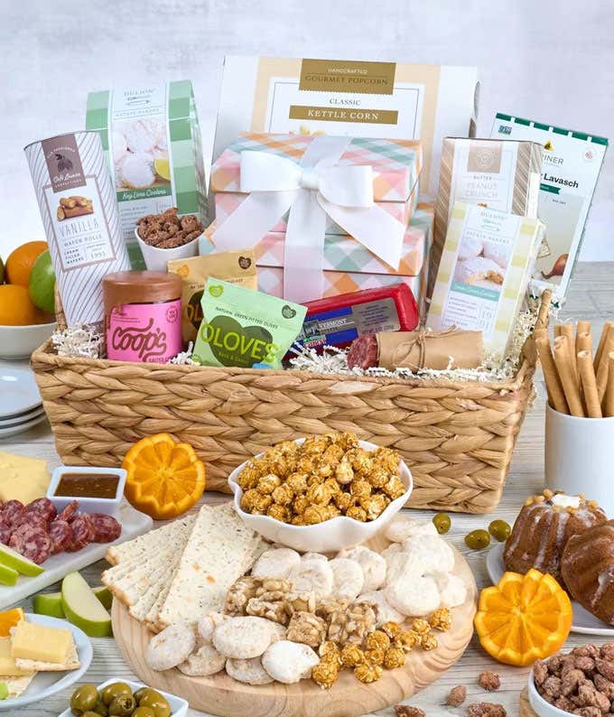 Image of a lavish gift basket filled with Green Apples, Oranges, Belgian Ale & Lemon Zest Salami, Seriously Sharp White Cheddar, and an array of gourmet treats, nestled in a Water Hyacinth Gift Basket.