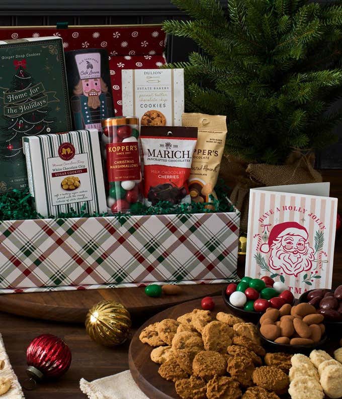Holiday gift box filled with ginger snap cookies, white chocolate chip sugar cookies, peanut butter chocolate chip cookies, chocolate-covered cherries, Christmas marshmallows, chocolate-covered almonds, and more, in a plaid container