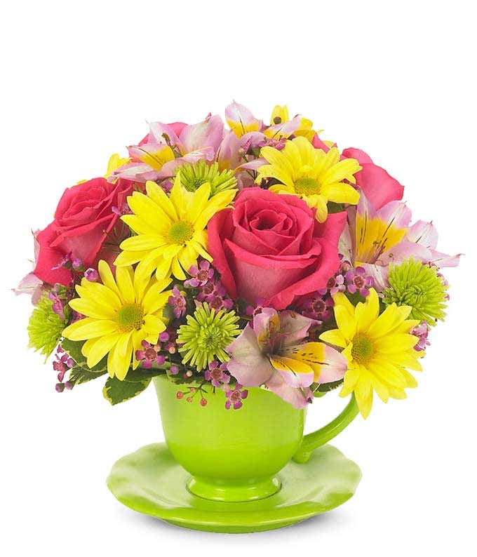 Hot pink roses, yellow daisies and green poms in a teacup vase