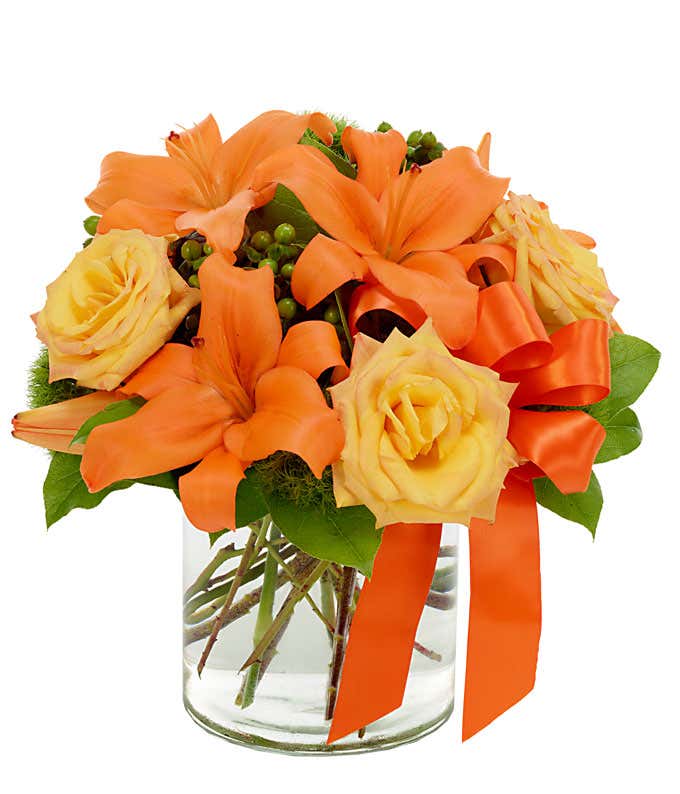 Orange asiatic lilies, yellow roses and green hypericum in circular vase