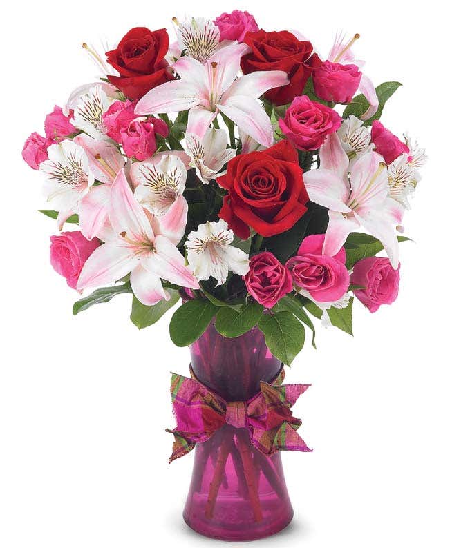 Red roses, pink lilies and pink spray roses in purple vase for Valentines Day