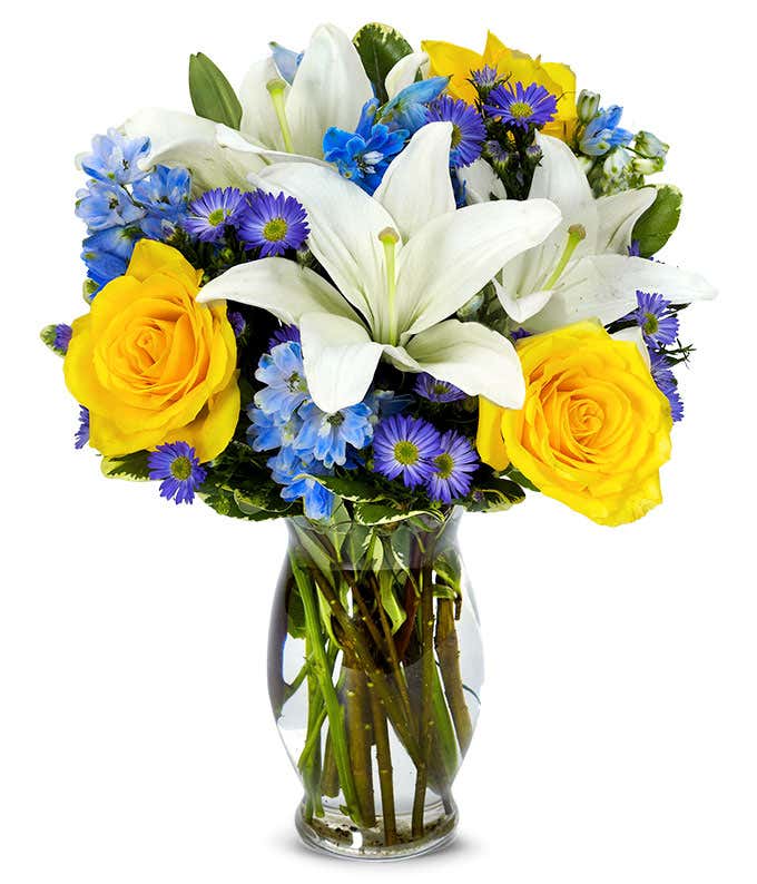 Yellow roses, blue delphinium and white lilies in a vase