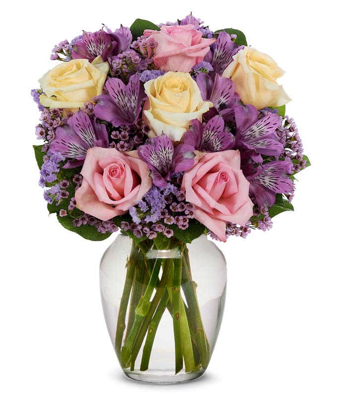 pink roses, yellow roses and purple alstroemeria in a clear glass vase