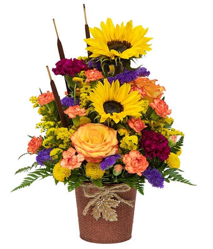 Mixed autumn with sunflowers, orange roses, orange carnations and maroon flowers.