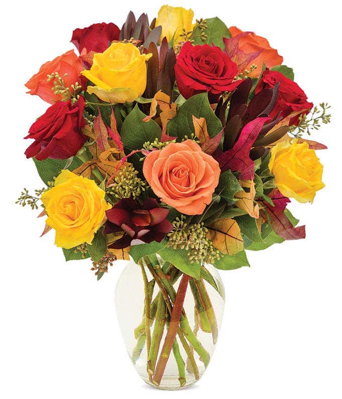 Red roses, orange roses and yellow roses in a fall bouquet with fake leaves