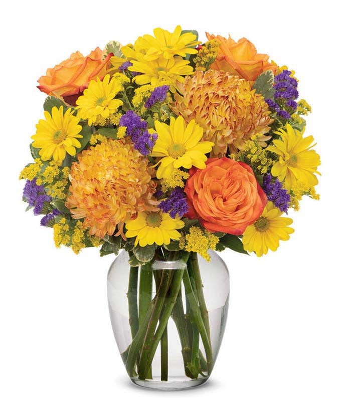 Bronze mums, Orange roses and yellow flowers in clear orange vase