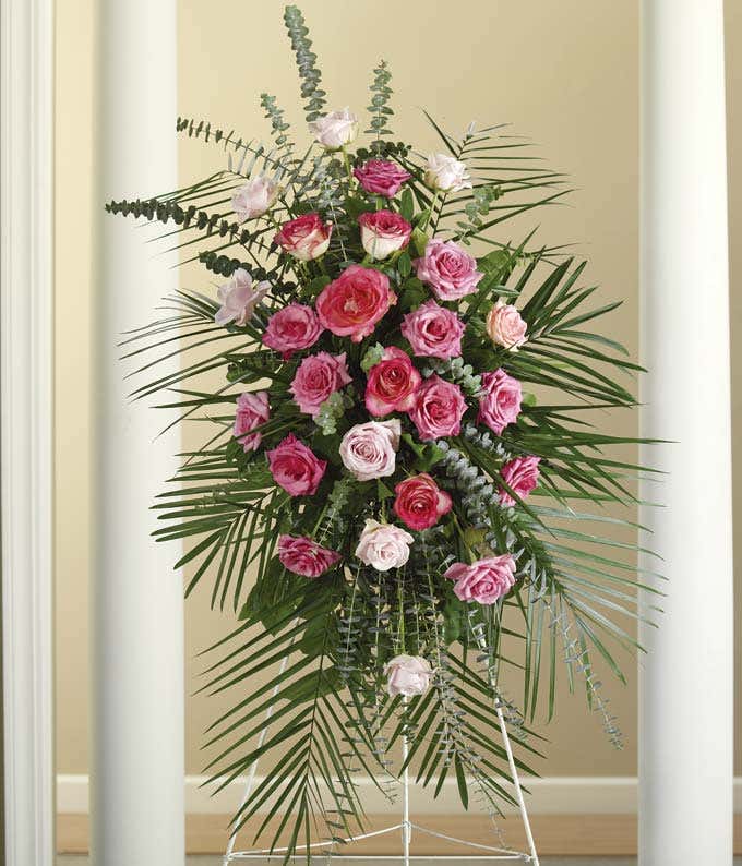 Mixed pink roses, spiral eucalyptus in a funeral standing spray