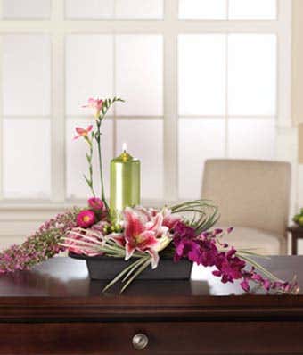 Pink lilies, asters and purple orchids with candle in arrangement