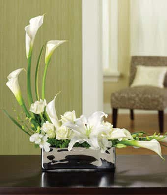 White calla lilies, white roses and white orchids in silver vase