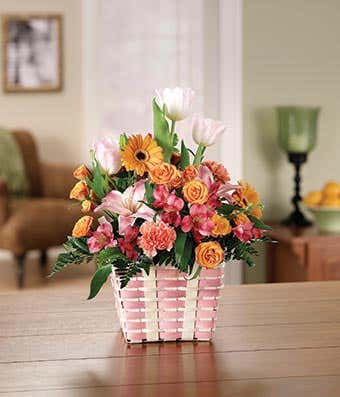 Pink tulips,pink alstroemeria and orange daisies in a basket