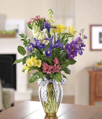 Purple irises, yellow and pink alstroemeria in glass vase