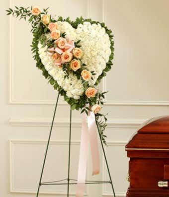 White carnations and peach rose break in funeral standing spray