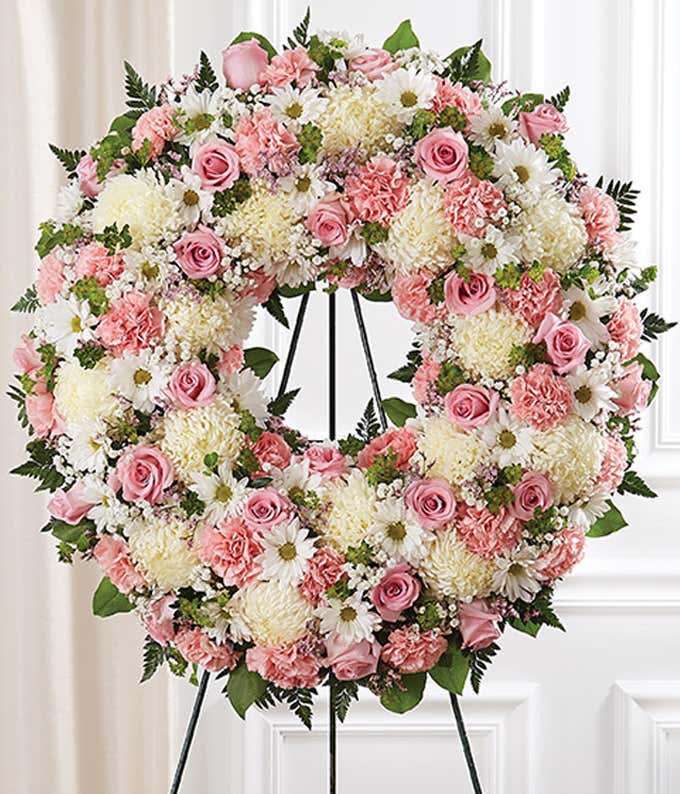 Pink roses, white daisies, and white mums in a funeral wreath