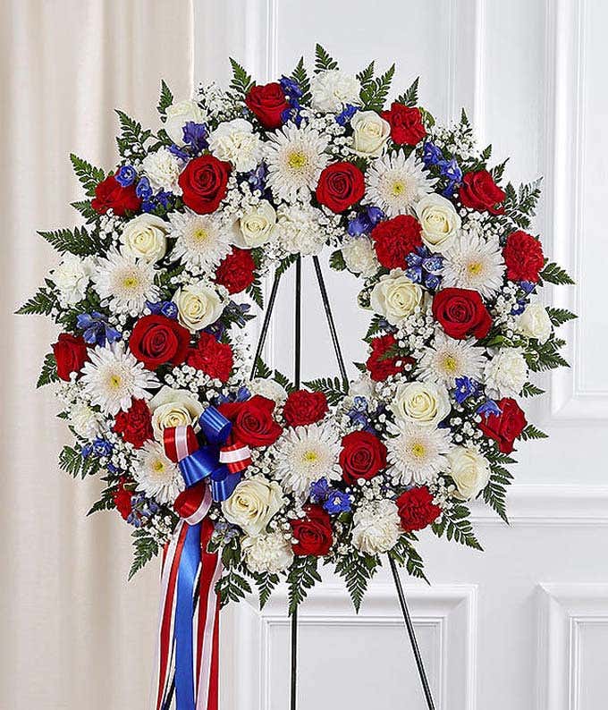 Red roses, white carnations and blue delphinium in funeral wreath