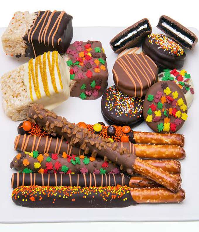 A delicious assortment featuring chocolate-covered rice treats, chocolate-covered OREO cookies, and chocolate-covered pretzels, all adorned with fall-themed edible decorations and coated in dark, white, and milk chocolate.