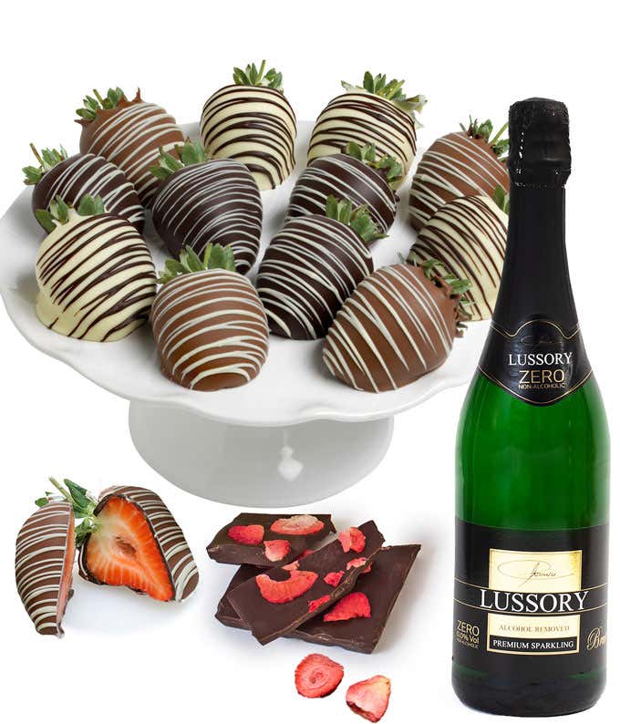 6 chocolate dipped strawberries with chocolate drizzles on a white platter next to a bottle of sparkling brut
