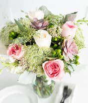 Alternative image 1 for A floral arrangement featuring white roses, pink roses, succulents, white stock, hypericum berries, Queen Anne's lace, white waxflower, and seeded eucalyptus, with an optional glass vase.