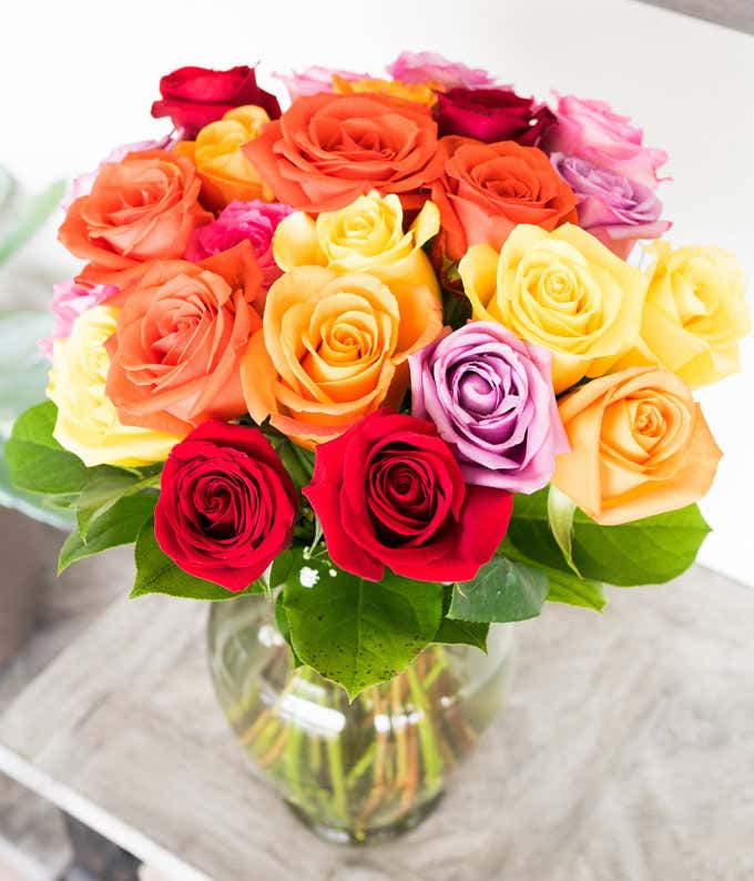 Two Dozen Assorted Rainbow Roses in a Clear Glass Vase 