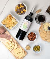 Alternative image 1 for A charcuterie gift set with Tuscan crisps, focaccia crackers, 3 cheeses, olives, mustard, sausage almonds, chocolate-covered popcorn and a bottle of Pinot Noir.