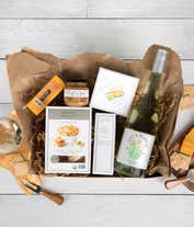 Alternative image 1 for A gift box with a bottle of California Chardonnay, two types of cheese, crackers, stone-ground mustard, and a summer sausage.