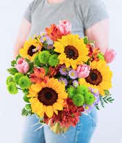 Alternative image 2 for A vibrant arrangement featuring sunflowers, pink tulips, red alstroemeria, purple Monte Casino asters, and green poms, optionally arranged in a glass vase. This lively mix offers a bright and cheerful display.