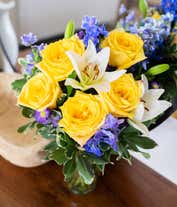 Alternative image 3 for An elegant floral arrangement featuring white Asiatic lilies, yellow roses, blue delphinium, and purple Monte Casino, optionally arranged in a glass vase. This vibrant mix offers a stunning and colorful display.