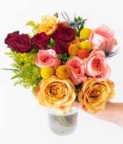 Alternative image 2 for  A vibrant floral arrangement featuring coral roses, peach roses, coral mini roses, yellow solidago, yellow craspedia, orange craspedia, and blue eryngium, complemented by a personal card message and optionally presented in a vase.