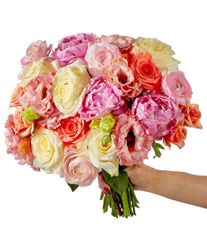 A serene bouquet featuring soft pink peonies and elegant roses, double lisianthus, miniature spray roses, all in a mix of cream, light pink, and light coral.