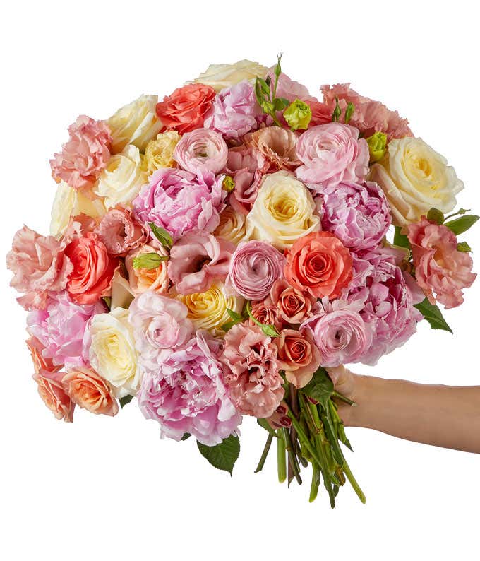A serene bouquet featuring soft pink peonies and elegant roses, double lisianthus, miniature spray roses, all in a mix of cream, light pink, and light coral.