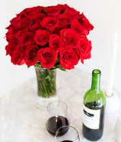 Alternative image 2 for Image of 50 long-stemmed red roses in a tall cylinder vase, accompanied by a box of chocolates and a cuddly teddy bear, the perfect gift for expressing love and affection.
