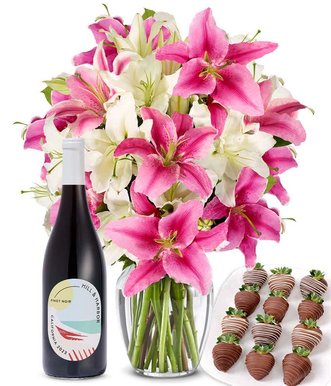 A bouquet of pink and white lilies arranged in a clear glass vase is paired with a bottle of Hill & Harbor Pinot Noir and 12 chocolate-covered strawberries.