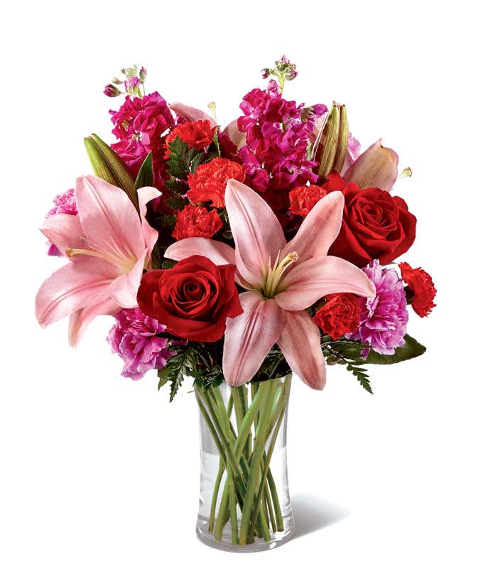 Glass vase with red roses, pink lilies, and red and pink carnations, mini carnations, and stock