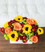 Alternative image 3 for A bright and cheerful floral arrangement featuring sunflowers, orange roses, butterscotch daisies, and green poms, all beautifully arranged in a wooden planter.