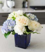 Alternative image 1 for A serene arrangement featuring white carnations, white roses, white alstroemeria, and blue hydrangea, elegantly presented in a blue cube vase. This beautiful mix creates a peaceful and soothing display.