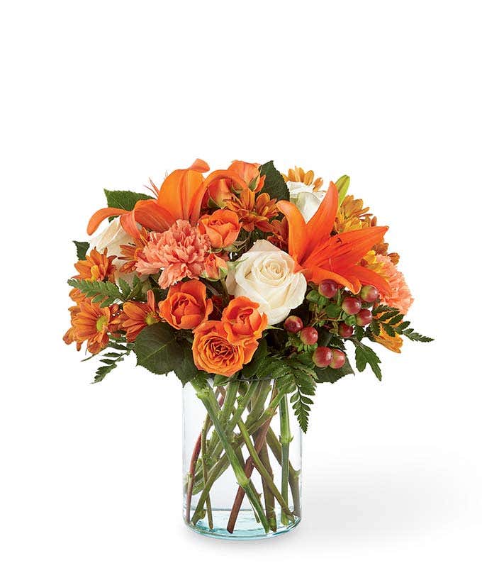 Orange lilies, cream roses and orange roses are arranged for Fall delivery