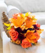 Alternative image 3 for A festive floral arrangement featuring orange lilies, orange roses, orange alstroemeria, and bronze daisies and poms, all beautifully displayed in a cornucopia basket.