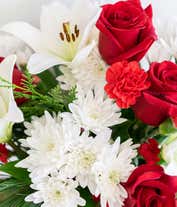 Alternative image 4 for A festive arrangement with red roses, white lilies, red carnations, red mini carnations, and white poms.