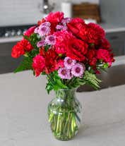 Alternative image 2 for Round, full, bouquet of red and hot pink flowers, in a clear vase