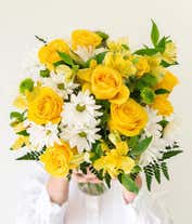 Alternative image 2 for A bright floral arrangement featuring yellow roses, white daisies, yellow alstroemeria, and green poms, elegantly arranged in a glass vase. This sunny mix offers a cheerful and uplifting display.