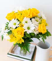 Alternative image 3 for A bright floral arrangement featuring yellow roses, white daisies, yellow alstroemeria, and green poms, elegantly arranged in a glass vase. This sunny mix offers a cheerful and uplifting display.