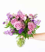 Alternative image 1 for A bouquet of lavender roses, purple alstroemeria and statice, with fresh floral greens, in a clear glass vase 