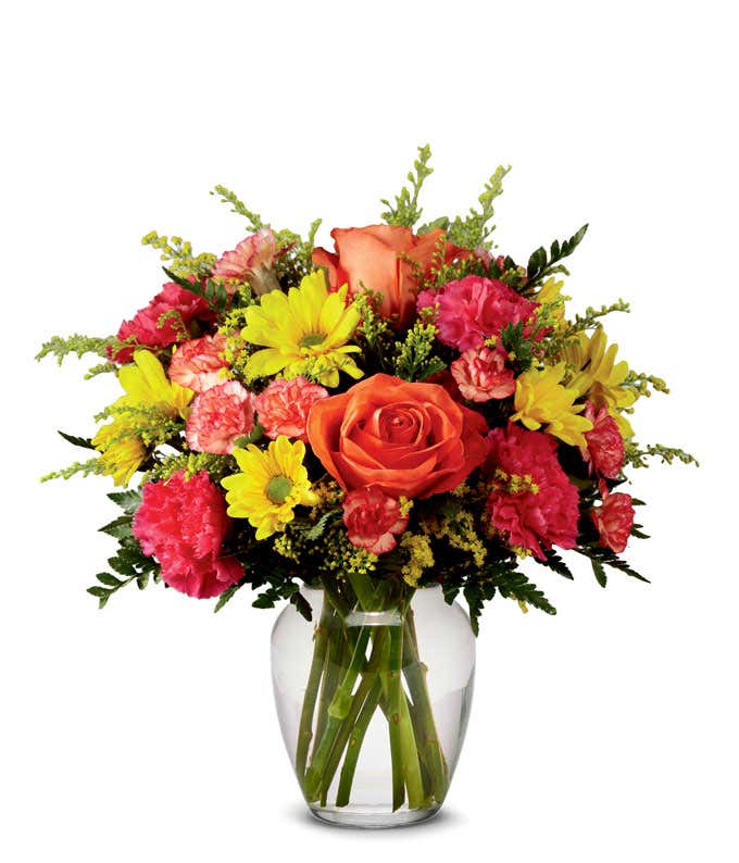 Orange roses, yellow daisies, with hot pink and orange carnations arranged into a clear glass vase
