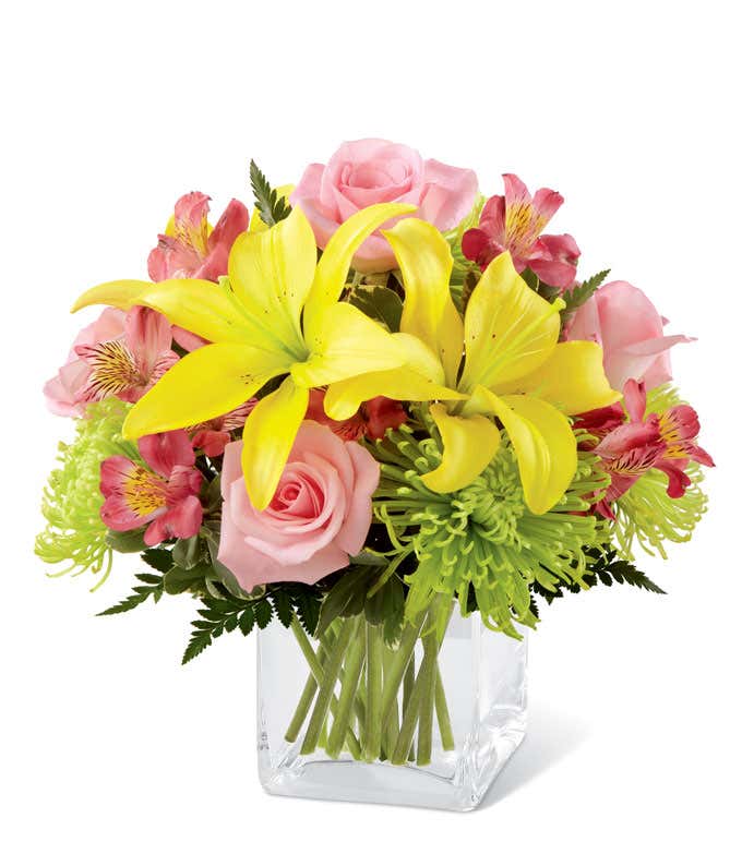 Yellow lilies, and pink roses, with green and pink mums and alstroemeria in a short cube vase