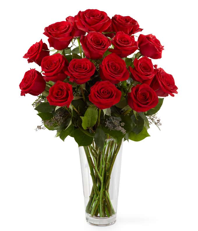 18 red roses with fresh floral greens in a tall clear glass vase