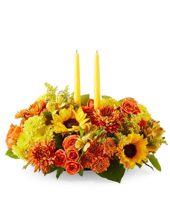 Yellow Sunflowers & Alstroemeria, Butterscotch & Yellow Poms, Orane Spray Roses, two yellow candle sticks in the center, against a white background