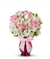 A charming arrangement featuring pink roses and white alstroemeria, beautifully presented in a pink fluted vase with a decorative ribbon. This elegant display offers a perfect blend of colors and sophistication for any occasion.