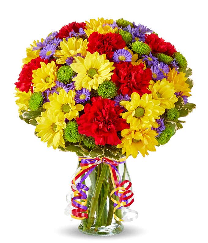 Yellow daisies, red carnations and green button pops in a glass vase
