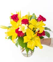 Alternative image 2 for A beautiful arrangement featuring yellow lilies and pink roses, elegantly presented in a clear glass vase. This vibrant mix offers a cheerful and uplifting display, perfect for brightening any space.